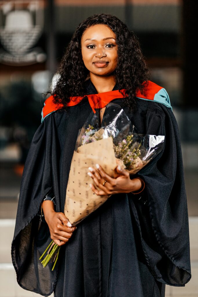 Graduating Woman Holding Bouquet in Academic Regalia
